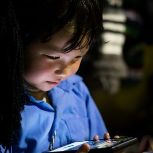 child using phone in dim light